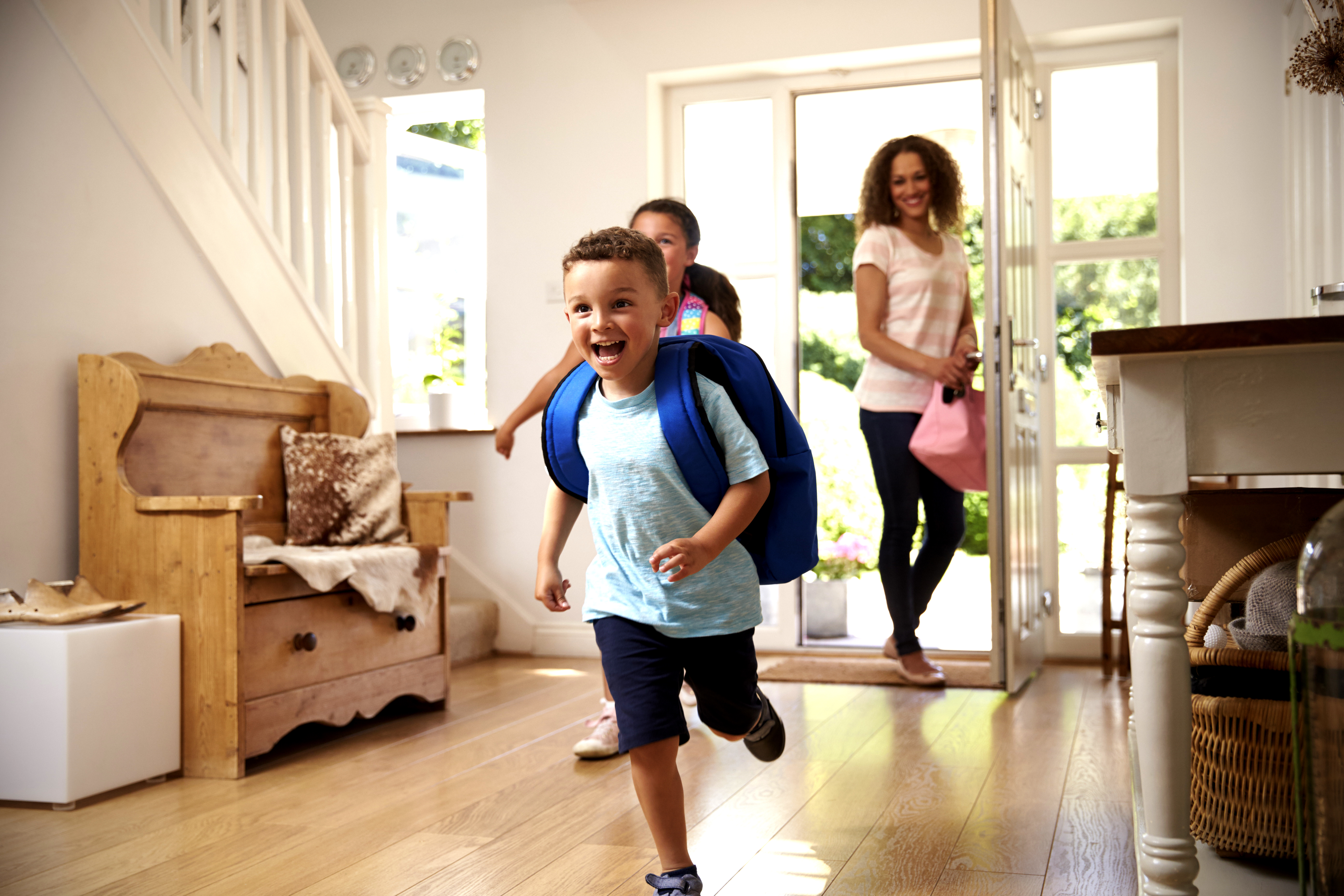 Family arriving home, with children running through the front door